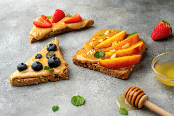 set of various toast with whole grain bread, peanut butter, honey, mint, peanut, nectarine, blueberry and strawberry. healthy breakfast concept