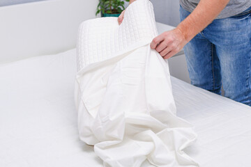 Fototapeta na wymiar A man puts a pillowcase on an orthopedic pillow.