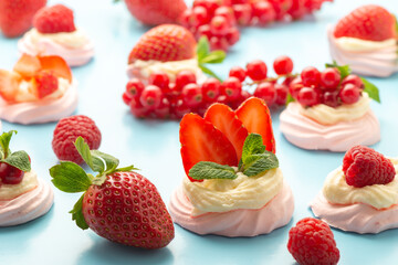Pavlova meringue cake with fresh berries and mint decorated fresh berries on blue background