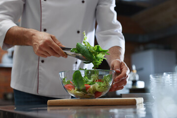 Professional chef making salad in restaurant kitchen, closeup