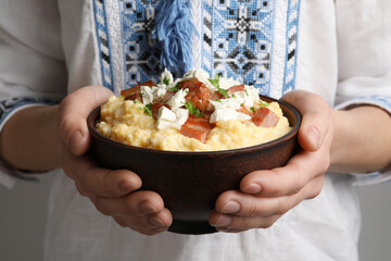 Woman holding bowl of delicious traditional Ukrainian banosh, closeup