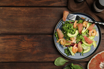 Delicious pomelo salad with shrimps served on wooden table, flat lay. Space for text