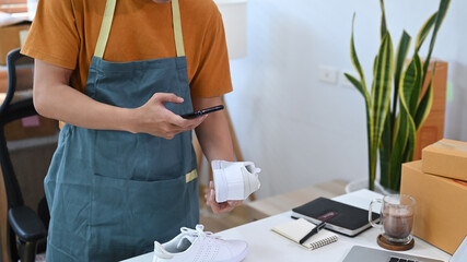 Young man using smart phone taking a photo of product for upload to website.