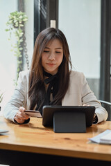 Attractive business woman holding credit card and using digital tablet for banking online.