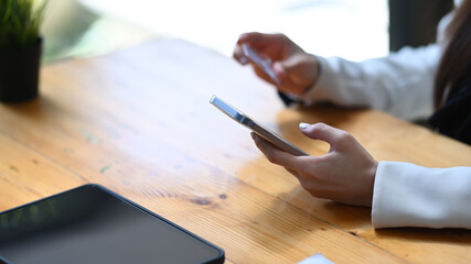Cropped shot young woman hand holding credit card and using smart phone.