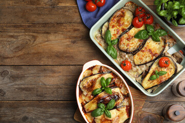 Delicious eggplant lasagna in baking dishes on wooden table, flat lay. Space for text