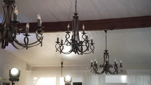 Black forged pendant chandeliers with retro style monograms on wooden ceiling. Shine modern large round led lights. Contrasting styles of antiquity and modernity.