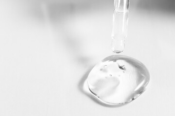 Transparent gel cosmetic drop on a white background with a pipette. Hyaluronic acid for skin repair, close-up.