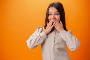 Happy teen girl excited and joyful against orange background