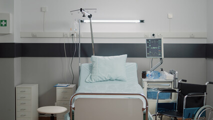 Empty hospital ward with medical equipment and tools for healthcare and healing. Nobody in emergency room bed at facility with IV drip bag, heart rate monitor and instruments for care - obrazy, fototapety, plakaty