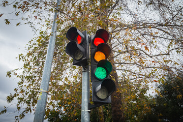 Traffic lights over urban intersection. Red, orange and green light - obrazy, fototapety, plakaty