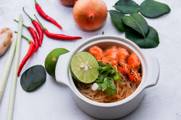 Shrimp potted with vermicelli is served in a white ceramic bowl with spices, chili, lemon, onion, kaffir lime leaves and galangal.