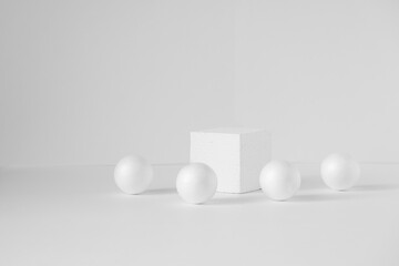 Geometric composition of a cube and balls on an isolated white background. Concept of 3d podium for presentations of packaging and cosmetics. Close-up, copy space.