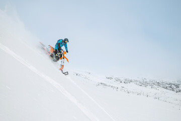 Fototapeta na wymiar Snowbike rider in mountain valley in beautiful snow powder. Modify dirt bike with snow splashes and trail. Snowmobile sport riding, winter sunny day