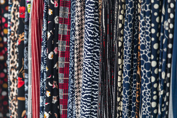 Large rows of pieces of fabric made of cotton, polyester, and other materials in different colors and prints of clothing, soft focus
