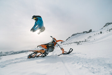 Jumping Snowbike rider in mountain valley in beautiful snow powder. Modify motorcycle with single...