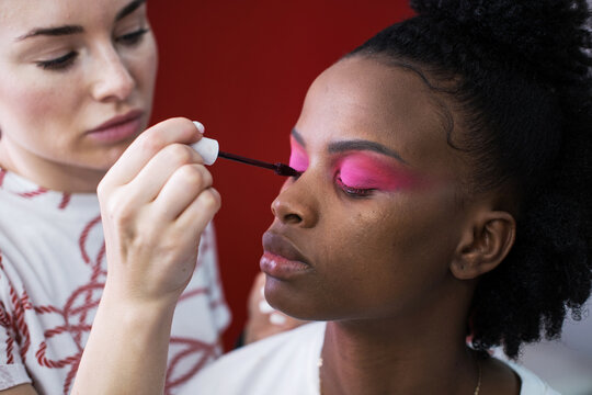 Make up artist doing makeup for african fashion model in studio