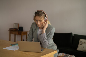 Young woman working at home with laptop and papers on desk and headphones. Home office concept.