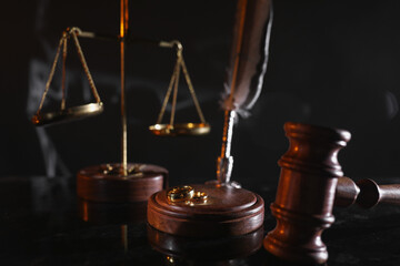 Divorce and law concept. Judge gavel and gold rings on a glossy table