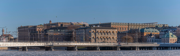 Fototapeta na wymiar Panorama view, a train bridge at the bay Riddarfjärden with ice floes background with government houses and the royal castle a sunny winter day in Stockholm