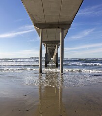 Water Level View Under Ocean Beach Pier Wooden Structure.  San Diego California Pacific Coast Scenic Detail on a Clear Sunny Winter Day
