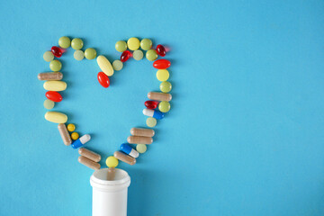 drugs, pills and capsules as heart and white bottle on blue background