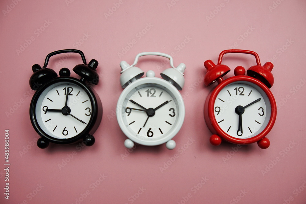 Poster top view of alarm clocks with different time flat lay composition on pink background