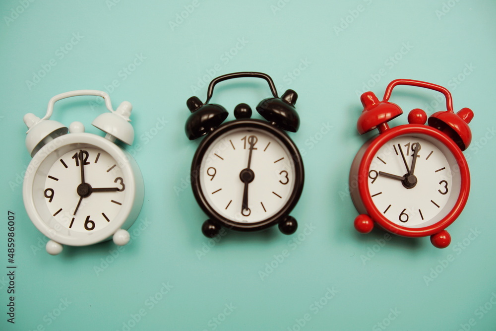 Poster top view of alarm clocks with different time flat lay composition on blue background