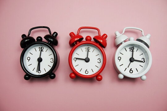 Alarm clocks with different time Flat lay composition on pink  background;