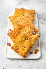 Layered dessert with raisins in a white plate on a light gray culinary background. Delicious homemade sweet puff pastry	