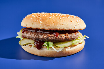 Beef burger blue background with hard shadow. American junk food minimal style. Hamburger trendy style.  Simple burger colour background.