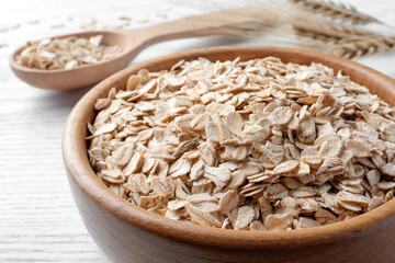 Oatmeal, bowl and spoon on white table, closeup