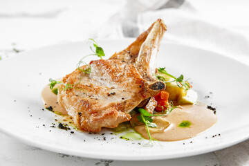 Roasted pork steak with vegetables garnish and sauce. Bone-in ribeye pork chops. Main course of pork in rustic style.