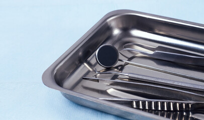 Metal tray with medical instruments, dental equipment, on a blue background, horizontal, no people,...