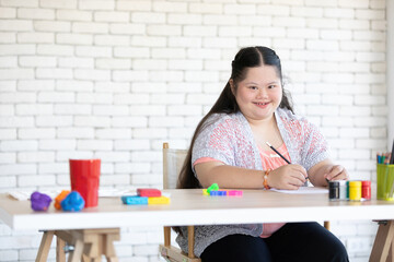 portrait down syndrome girl holding pencil and writing on paper