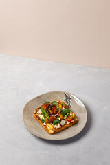 Bruschetta with octopus, vegetables and sauce on gray ceramic plate. Toast with octopus in contemporary style. Chef concept bruschetta in modern ceramic dishware. Handmade dinner plate.