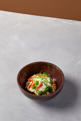Chef salad with crab, quinoa, vegetables and edamame beans on dark homemade ceramic bowl. Salad bowl with crab, avocado, cream sauce in modern serveware. Modern dishware on concrete background.
