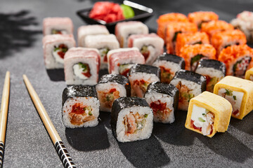 Maki sushi set on dark background. Big maki set with variety rolls.Composition from sushi rolls and hosomaki. Style concept sushi menu with black background, leaves and hard shadow.