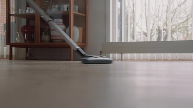 Young male cleaning the house with a Vacuum Cleaner Cleaning the wooden floor Zoom In Detail