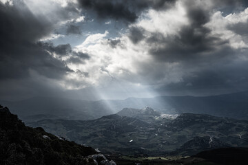 Scenic view of sunlight on mountain through cloud