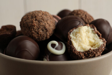 Many different delicious chocolate truffles in bowl, closeup