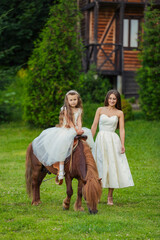 mother with daughter and pony walking in the yard