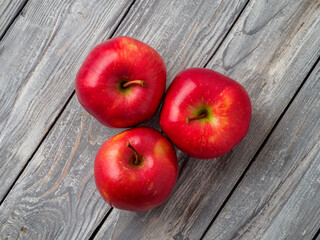 Three red apples on wooden background.