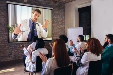 Group of young doctors having online conference  in convention center.