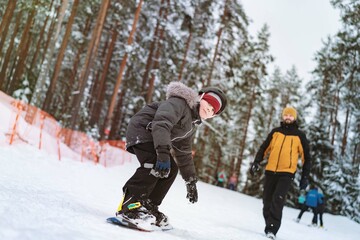 Fototapeta na wymiar little boy learning to ride on snowboard