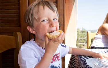 Portrait of boy eating tart at restaurant