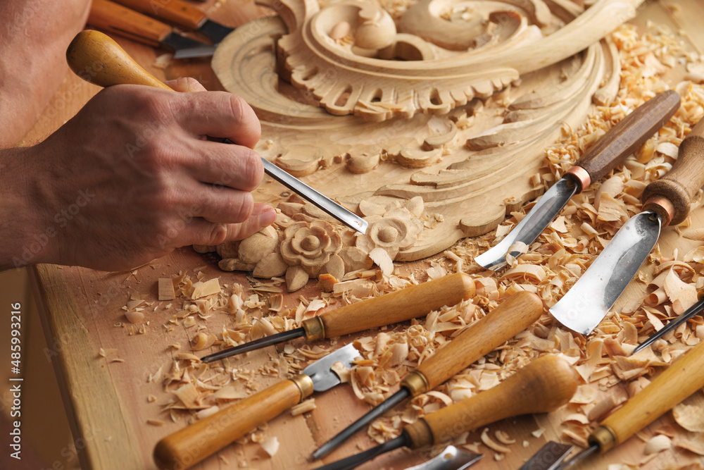 Wall mural wood carving. carpenter's hands use chiesel. senior wood carving professional during work. man worki