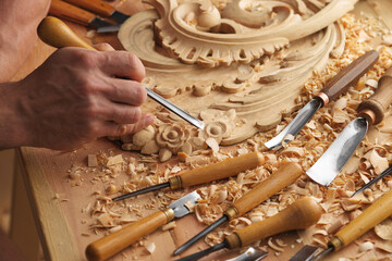 Wood carving. Carpenter's hands use chiesel. Senior wood carving professional during work. Man...