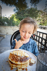Boy eating pancake at outdoor cafe