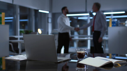 Blur shot of business partner shaking hands late in office